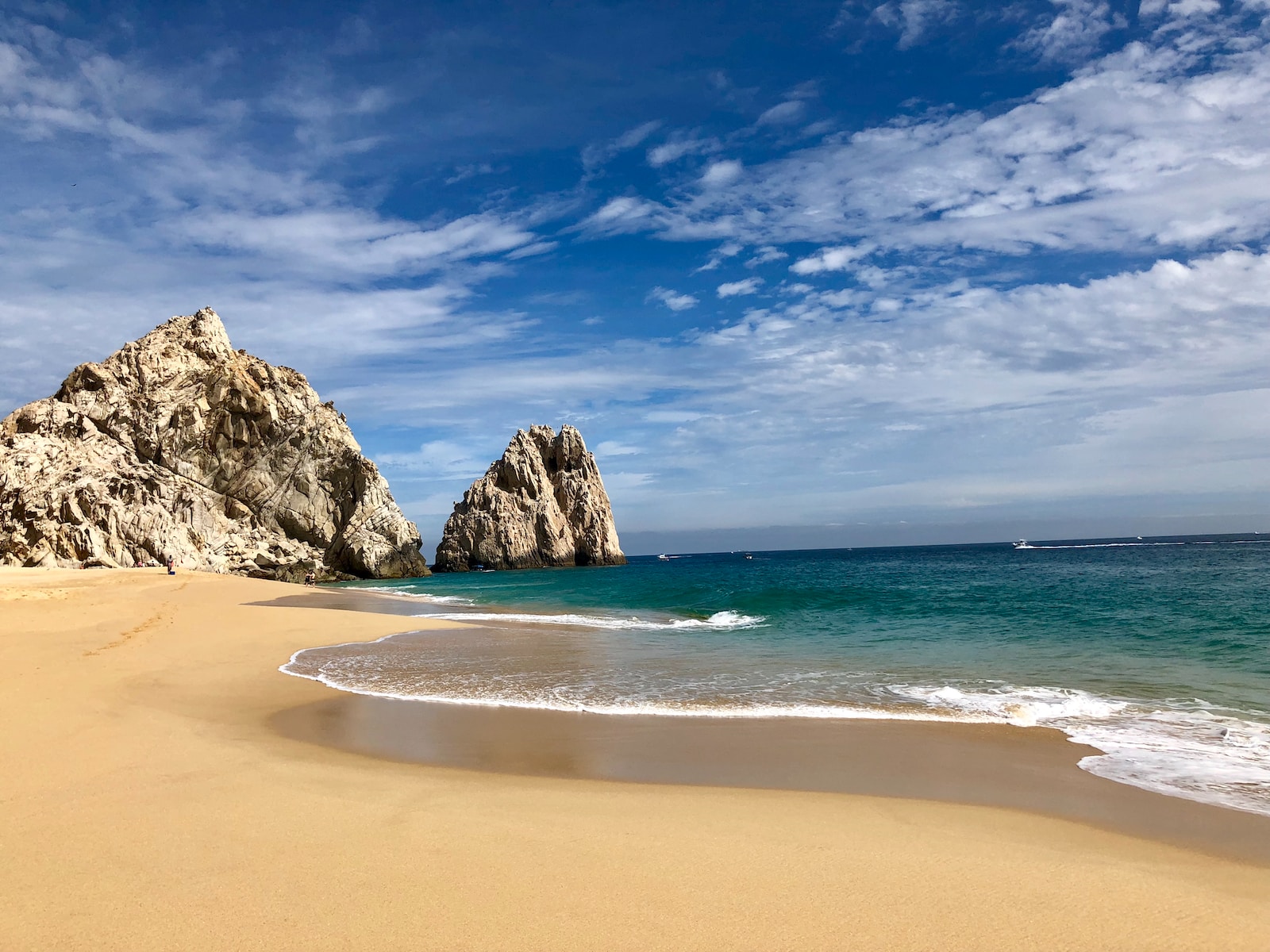 brown rock formation on sea shore under blue sky and white clouds during daytime